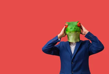  man with googly-eyed frog mask surprised with his hands on his head on red background © Avelino