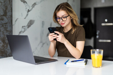 Beautiful woman working on laptop use phone in the kitchen