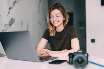 Woman photographer working from home on laptop - obrazy, fototapety, plakaty