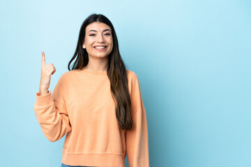 Young brunette girl over isolated blue background pointing up a great idea