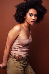 Naklejka premium pretty young african american woman with curly hair posing cheerful gesturing on brown background, lifestyle people concept