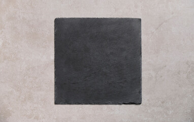 Empty square slate plate on old gray concrete background. Top view with copy space for your text.