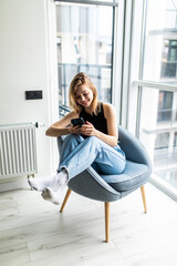 Young woman sitting comfortable on the chairuse on the phone in the living room