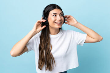 Young brunette girl over isolated blue background listening music and singing