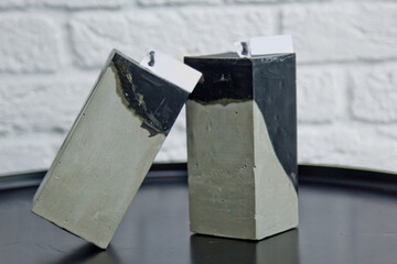 homemade multi-colored candles with concrete on the background of a white wall. handmade decor close-up. Details of a colored cube and tube loft candle