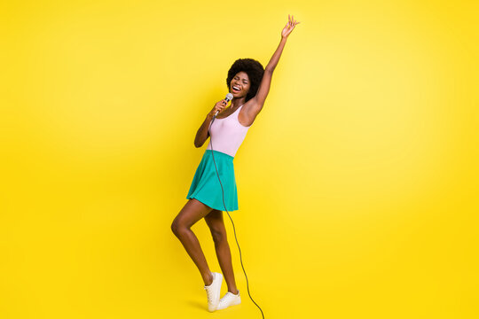 Full length profile side photo of brown afro american volume haired beautiful woman sing mic isolated on yellow color background