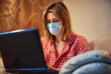 Young businesswoman in a medical protective mask works from home