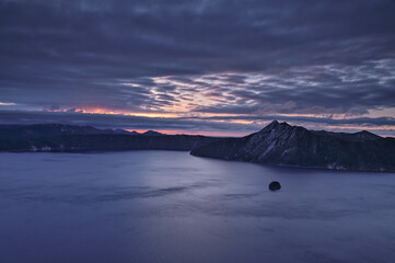 薄い雲の広がる夜明けの湖。日本の北海道の摩周湖。
