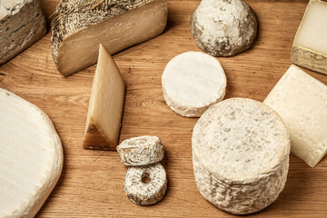 Various Types Of Cheese Laid Out On A Wooden Board.