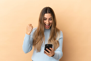 Fototapeta premium Young caucasian woman isolated on beige background surprised and sending a message