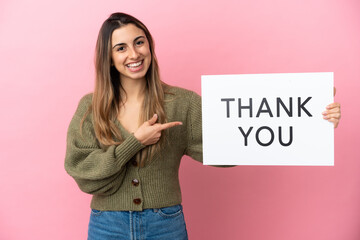 Young caucasian woman isolated on pink background holding a placard with text THANK YOU and ...