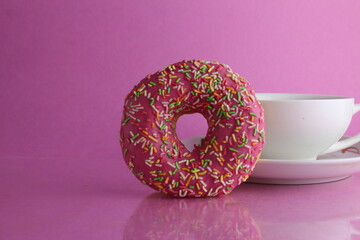 Still life sweet donut berliner chocolate pink yellow on a pink fuchsia background with a place for text and a copypipe picture