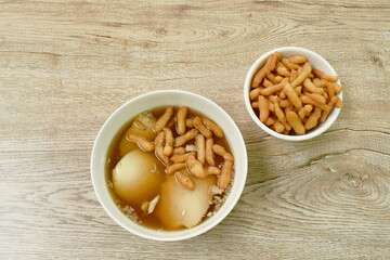boiled soybean tofu pudding custard in ginger juice soup topping mini crispy fried Chinese dough in bowl on table