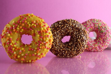 Still life sweet donut berliner chocolate pink yellow on a pink fuchsia background with a place for text and a copypipe picture