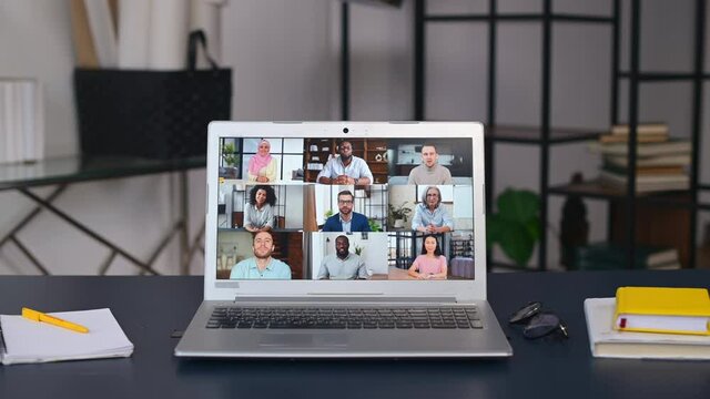 Online meeting of diverse work team, video call, video conference. App for video connection on laptop screen in office, profiles of several people, office staff on the monitor