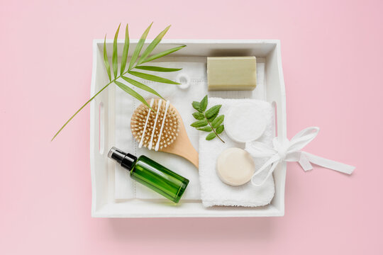 Still life von Kosmetik Artikel und einer gr&uuml;nen Parf&uuml;m Flasche auf einem wei&szlig;en Serviertablett. Draufsicht, pinker Hintergrund.
