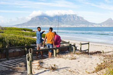 African american father and his two sons with fishing rods walking together on the bridge
