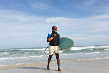 African american senior man with surfboard walking towards the beach