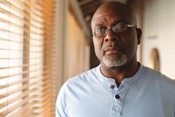 Portrait of thoughtful african american senior man standing at home
