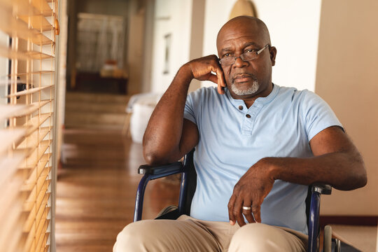 Stressed disabled african american senior man sitting on the wheel chair at home