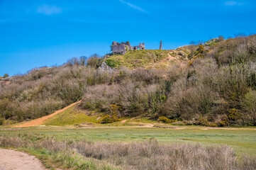 A view towards the castle ruins at the Three Cliffs Bay, Gower Peninsula, Swansea, South Wales on a sunny day