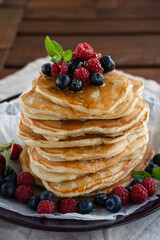 Pancakes with  honey and berries on brown wooden background
