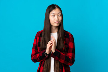 Young Chinese girl over isolated blue background scheming something
