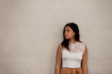 portrait of young latin looking to her right side on the street with short white shirt and brown skirt and copy space