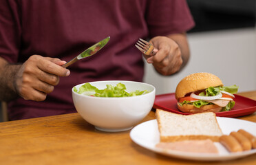 A young man eating breakfast. Breakfast set includes bread, bacon, salad and sausage.
