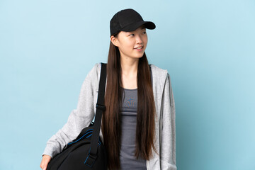 Young sport Chinese  woman with sport bag over isolated blue background thinking an idea while looking up