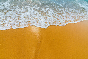 Soft blue ocean wave on clean sandy beach