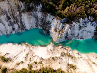 Fototapeta na wymiar Artificial lake in a chalk quarry in Belarus at Krasnoselsky. Turquoise background of the clear water in summer season in open pit. Technogenic mountains formed during chalk mining. Amazing landscape