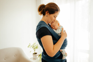 Attachment parenting concept. Young mother with baby in sling - 430386791