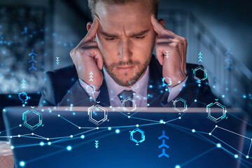 Handsome businessman in suit at workplace working with laptop to optimize development by implying...