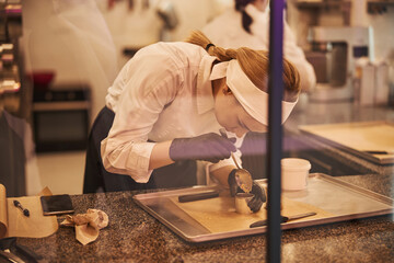 Focused woman in chef uniform working hard on making desserts