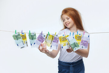 beautiful red-haired girl hangs euro banknotes on a rope