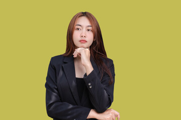 Portrait of Asian young businesswoman thinking creating new plan or solving over problem. Thoughtful beautiful female crossed arms and fingers on chin looking at camera isolated on green background