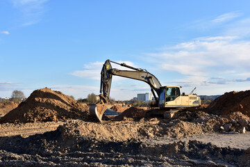 Excavator on earthworks at construction site. Backhoe on earthmoving and foundation work. Heavy machinery and equipment.