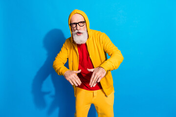 Photo of funky funny cool mature man in glasses dancing wear yellow tracksuit isolated on blue color background