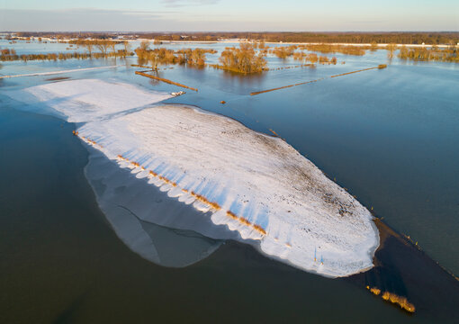 Aerial view of snow-covered island, a higher part of submerged floodplain of river IJssel during high water in winter near Welsum, Overijssel, Netherlands.