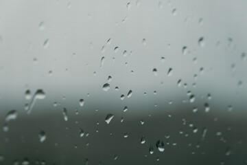 rain drops during raining in rainy day outside window glass with blurred background with water droplet flow down the surface