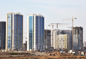 Fototapeta na wymiar Tower crane on construction of a residential building. Cranes on formworks. Construction the building or multi-storey homes. Instal concrete wall rebar. Renovation concept. Real Estate