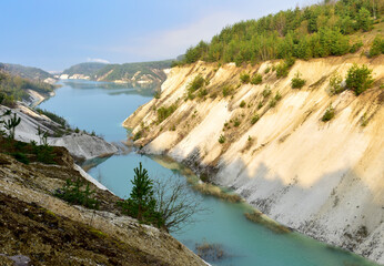 Obraz na płótnie Canvas Artificial lake in a chalk quarry in Belarus at Krasnoselsky. Turquoise background of the clear water in summer season in open pit. Technogenic mountains formed during chalk mining. Amazing landscape