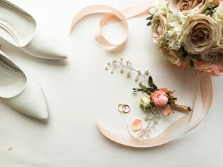 Pink flowers, pearl jewelry and two gold wedding rings on a white background. Wedding concept. Isolated	