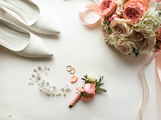 Pink flowers, pearl jewelry and two gold wedding rings on a white background. Wedding concept. Isolated	