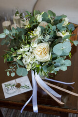 Close up of beautiful tender wedding bouquet with white roses and eustoma flowers on brown wood table