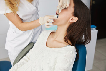 Obraz na płótnie Canvas Dental worker placing plaster stone into female patient mouth