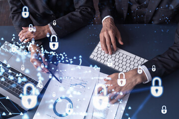 Two businesspeople man and woman working on the project to protect cyber security of international company. Padlock Hologram icons over the table with documents. Formal wear. Workspace.