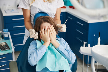 Boy covering his face and refusing dental operation