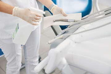 Dental office worker cleaning handpiece with disinfectant spray